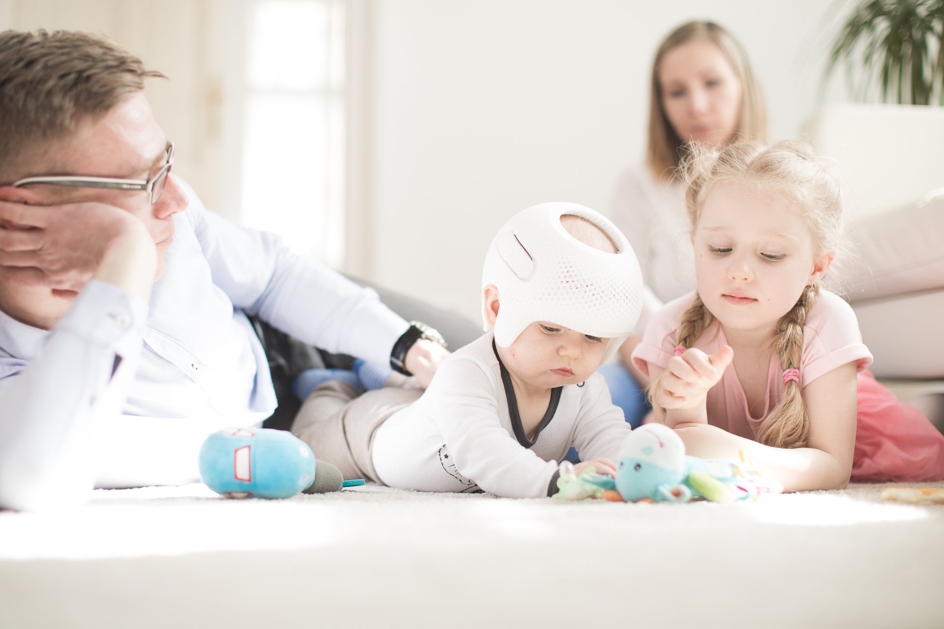 Father and kids playing with toy on floor.